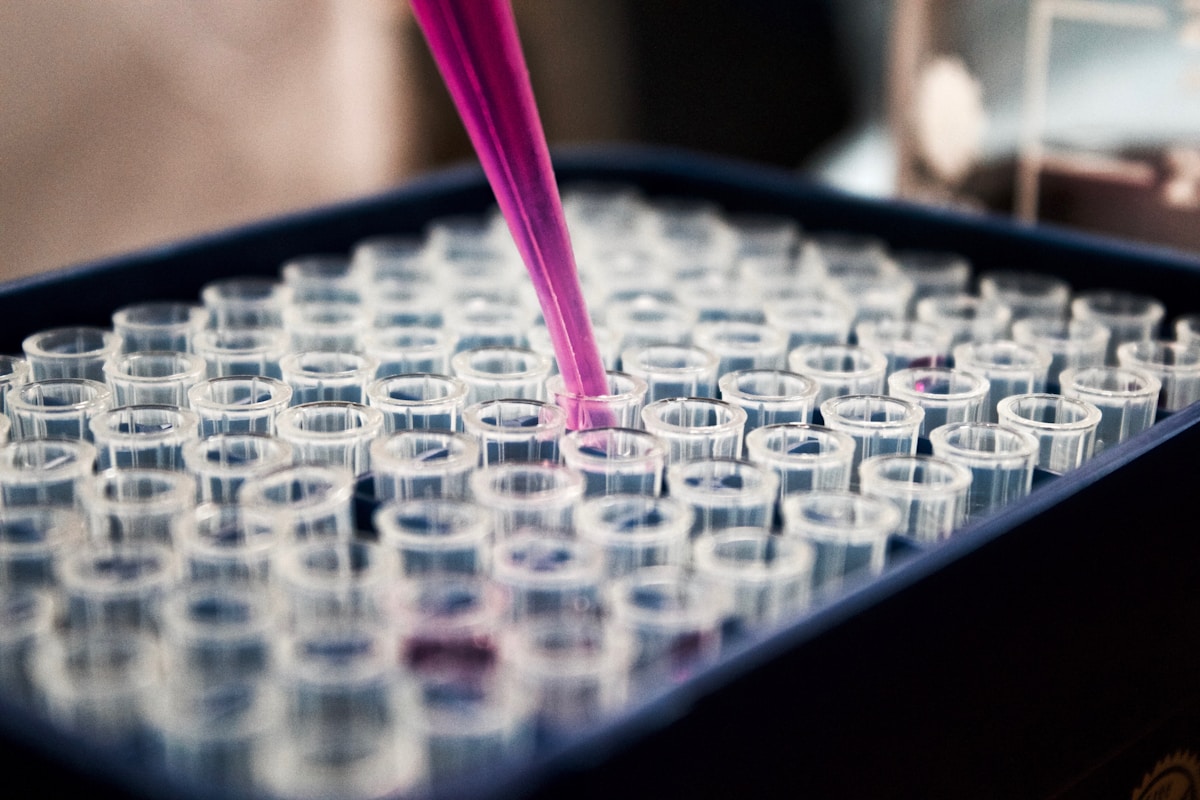 Pipette adding pink dye to microplate — precision dye formulation testing